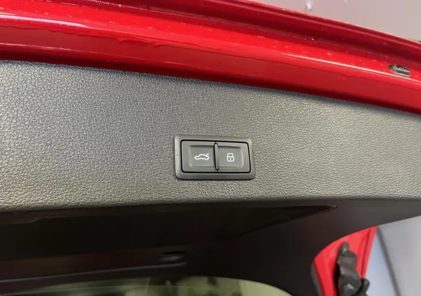 Boutons d'ouverture et de verrouillage du hayon électrique sur la partie intérieure rouge du coffre d'un Audi Q2 rouge S line 2024