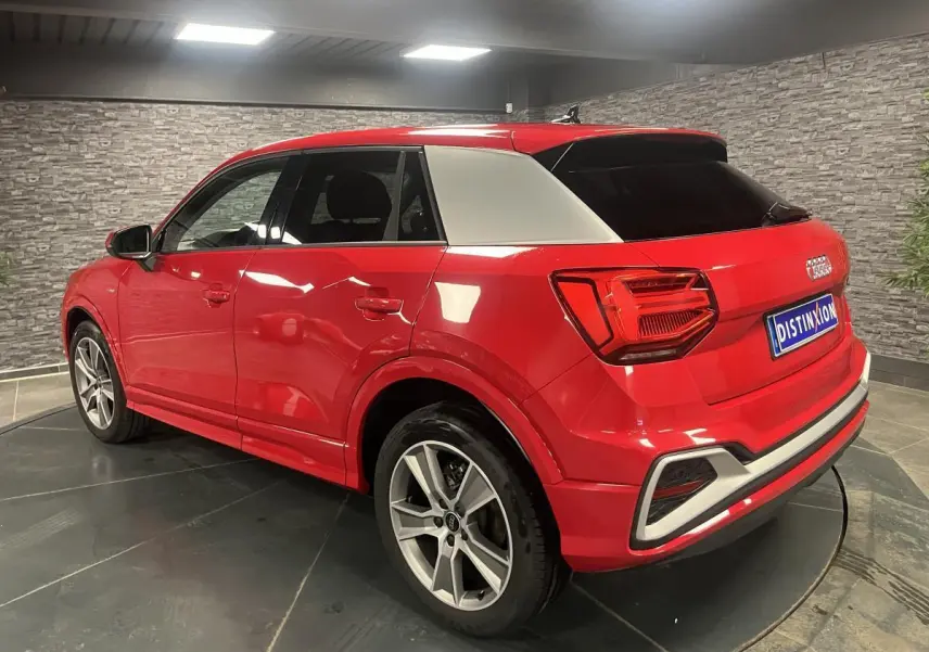 Audi Q2 rouge vue 3/4 arrière droit avec toit contrasté blanc et jantes sport 5 branches titanium mat.