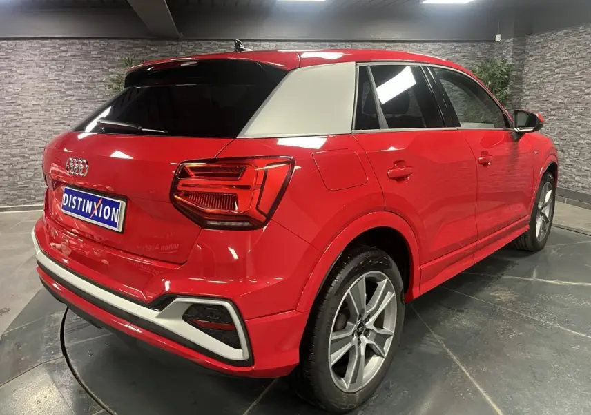 Audi Q2 rouge vue 3/4 arrière droit avec toit blanc contrasté et jantes sport 5 branches titanium mat.