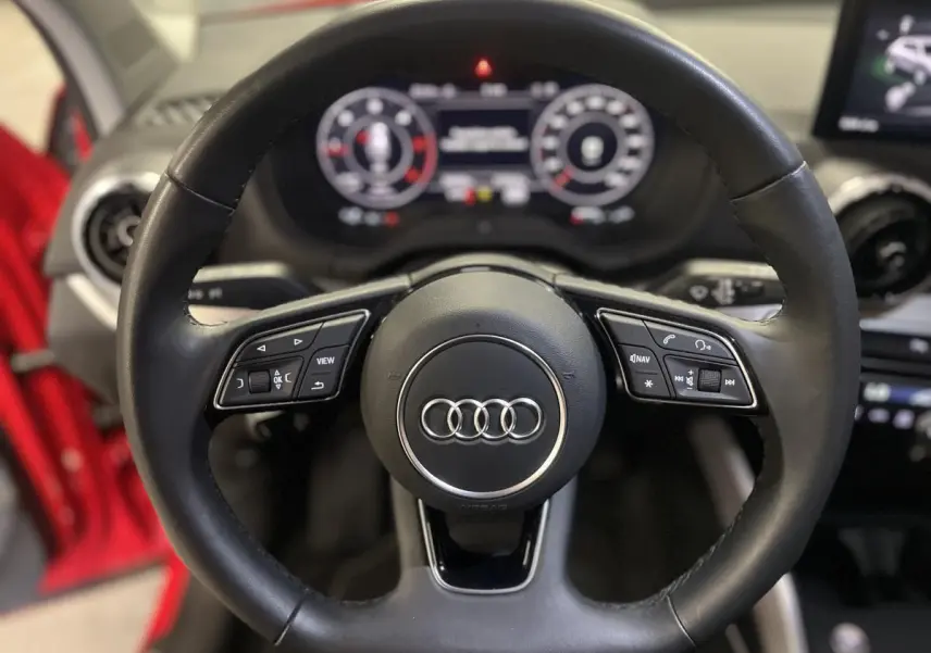 Volant sport en cuir multifonction de l'Audi Q2 rouge 2024, vue rapprochée du poste de conduite