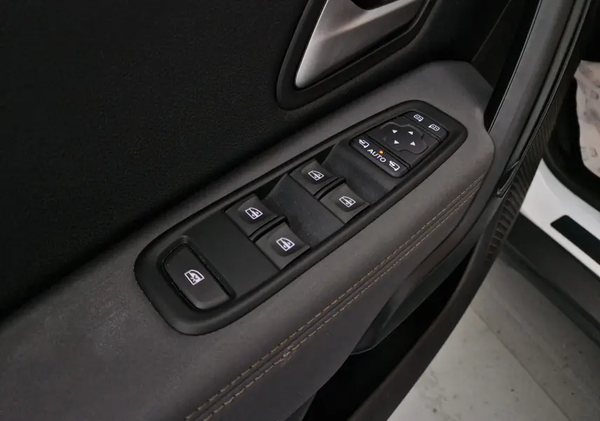 Gros plan sur les commandes de lève-vitres et rétroviseurs côté gauche du Dacia Duster blanc 2024 4x4.