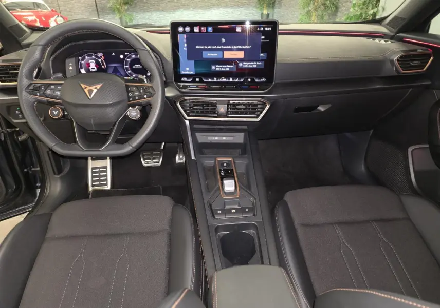 Vue intérieure avant du CUPRA Formentor 2025 avec tableau de bord noir, volant sport et écran tactile central.