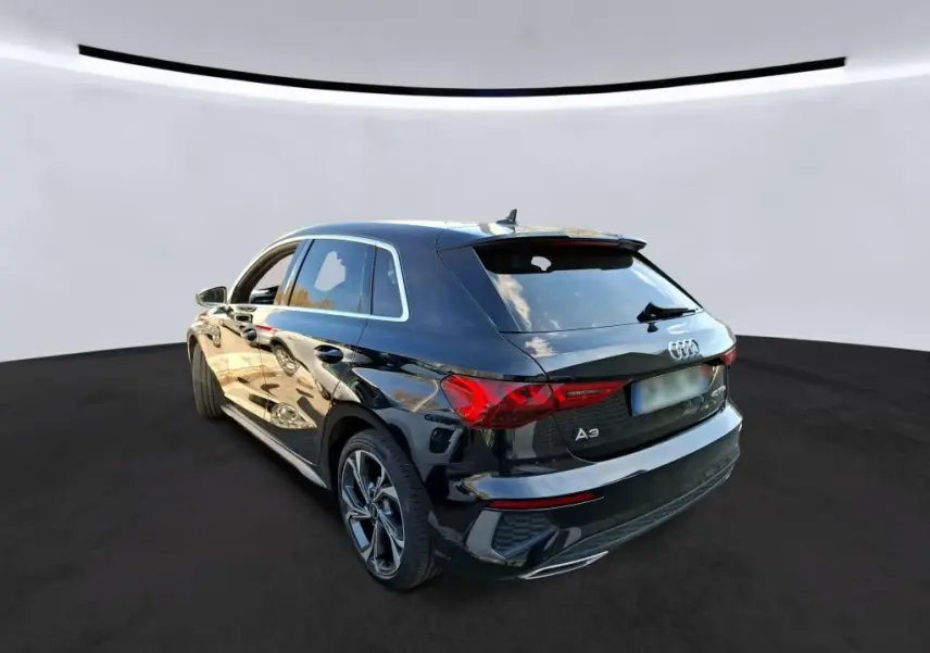 Audi A3 Sportback noir en 3/4 avant droit, avec jantes alliage 18'' et calandre hexagonale distinctive S line.