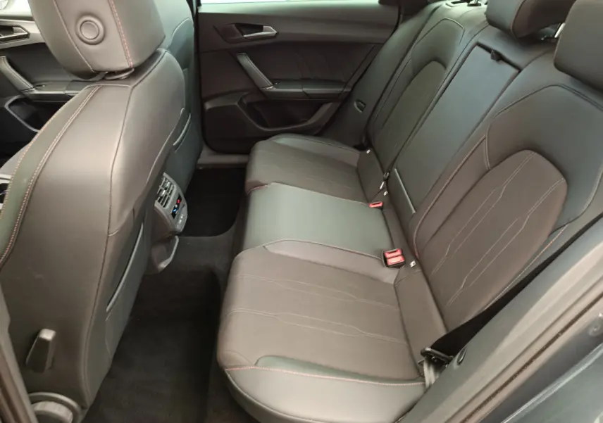 Vue intérieure côté droit des sièges arrière en cuir noir avec surpiqûres orange d'une CUPRA LEON ST 2024 gris foncé.