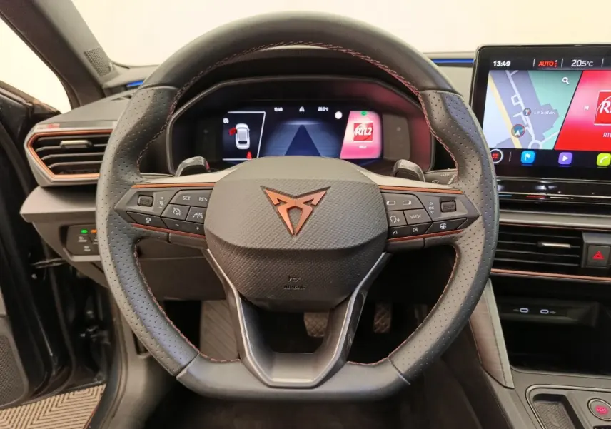 Vue intérieure centrée sur le volant cuir perforé avec logo CUPRA et écran tactile du tableau de bord du Leon ST 2024.