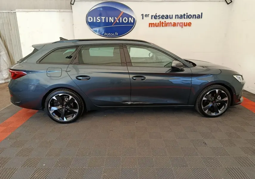 Profil droit d'une CUPRA LEON ST 1.5 eTSI 150 DSG7 gris foncé, avec jantes alliage noires et toit ouvrant visible.