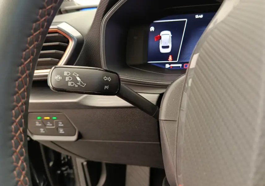Gros plan sur la manette de clignotant à gauche du volant dans l'habitacle sombre de la CUPRA Leon ST 2024.