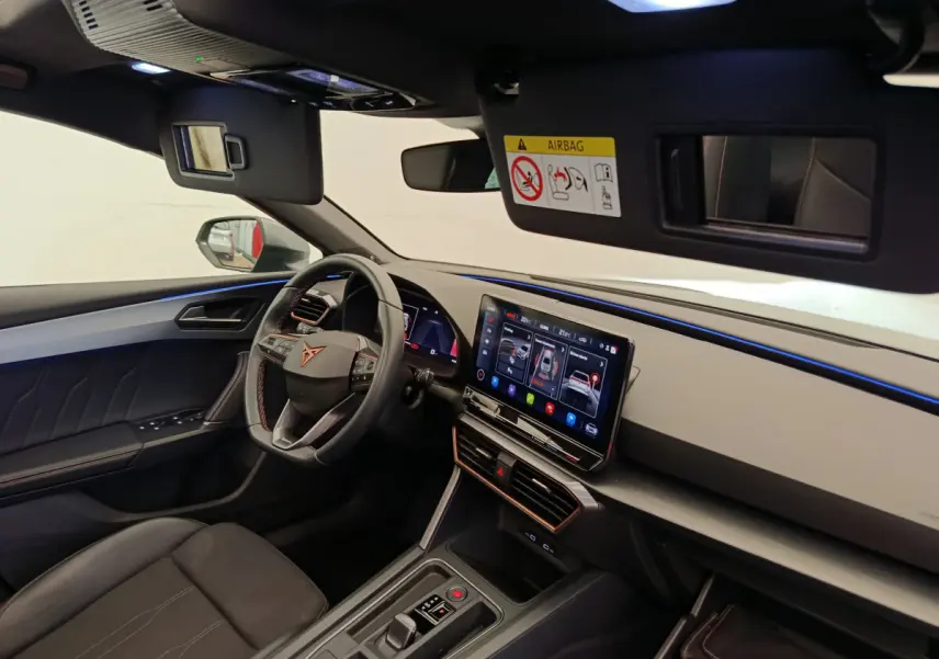 Intérieur côté conducteur de la CUPRA LEON ST 2024, tableau de bord moderne avec écran tactile et volant cuir noir.