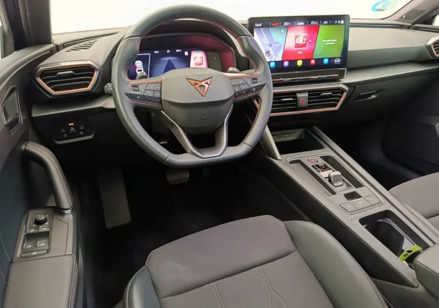 Intérieur de la CUPRA LEON ST 2024, vue du poste de conduite avec volant cuir, écran tactile 12 pouces et console centrale noire.
