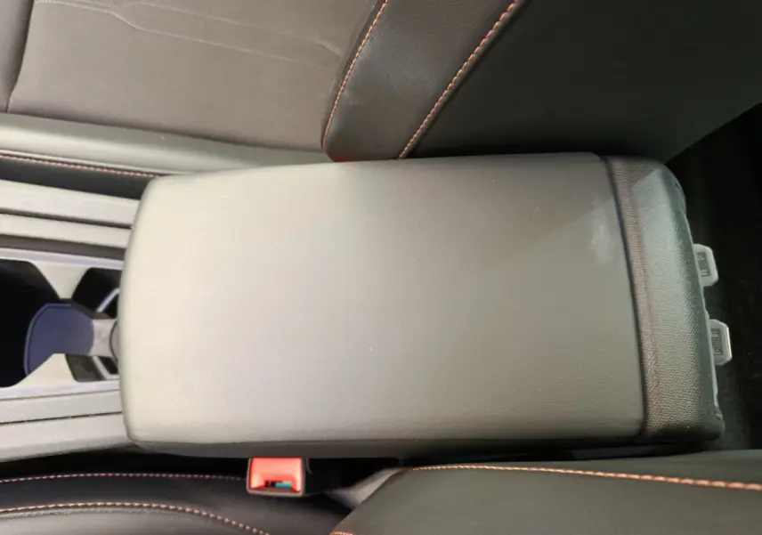 Accoudoir central noir avec surpiqûres orange dans l'habitacle du CUPRA LEON ST gris foncé 2024.