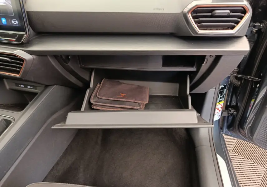 Vue intérieure du coffre à gants ouvert avec pochette noire dans une CUPRA LEON ST 2024 gris foncé.