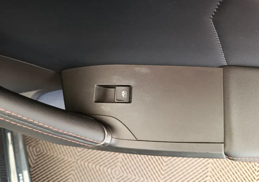 Gros plan sur le bouton de lève-vitre côté gauche dans l'intérieur noir avec surpiqûres rouges d'une CUPRA LEON ST 2024.