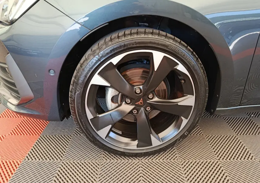 Gros plan sur la roue avant gauche gris foncé d'une CUPRA LEON ST 1.5 eTSI 150 DSG7 V avec jante noire et argentée distinctive.