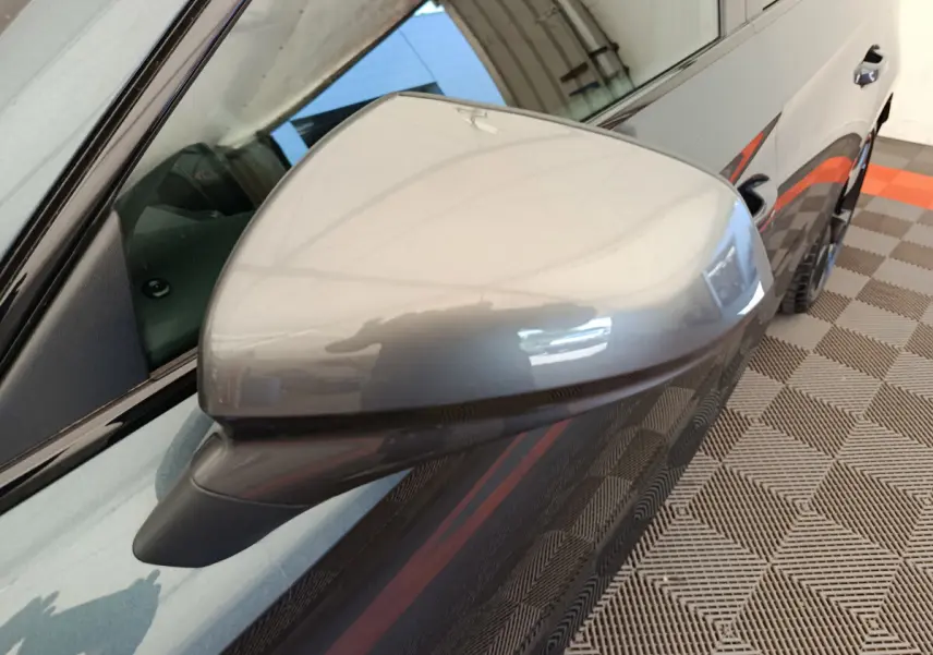 Rétroviseur droit gris foncé de la CUPRA LEON ST 2024, avec carrosserie et jante partiellement visibles en arrière-plan.