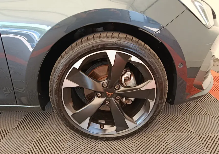 Gros plan sur la roue avant droite d'une CUPRA LEON ST gris foncé, avec jante alliage noire et grise distinctive.