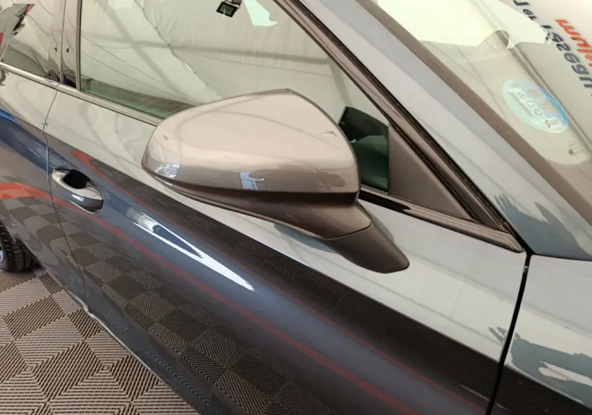 Vue rapprochée du rétroviseur côté gauche d'une CUPRA LEON ST gris foncé avec portière et vitre avant visibles.