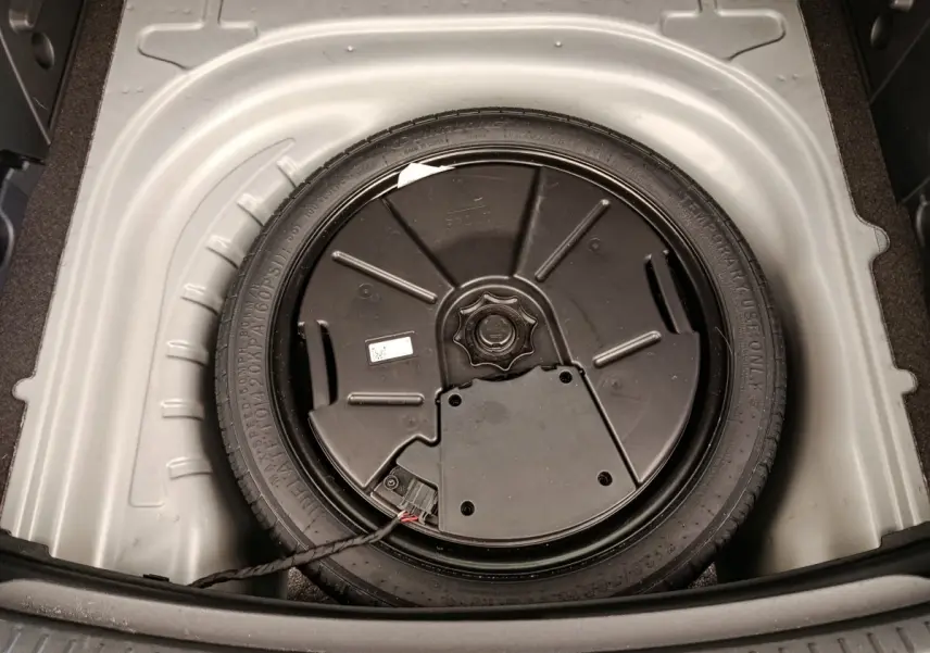 Vue plongeante sur la roue galette de secours dans le coffre gris foncé d'une CUPRA LEON ST 2024