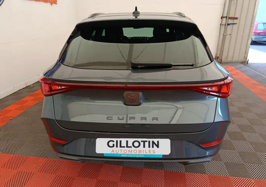 Vue arrière d'une CUPRA LEON ST gris foncé avec feux arrière LED reliés et logo CUPRA central lumineux.