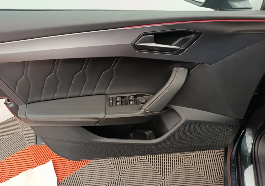 Vue côté gauche de la porte intérieure noire avec surpiqûres rouges et poignée en cuir du CUPRA LEON ST 2024 gris foncé