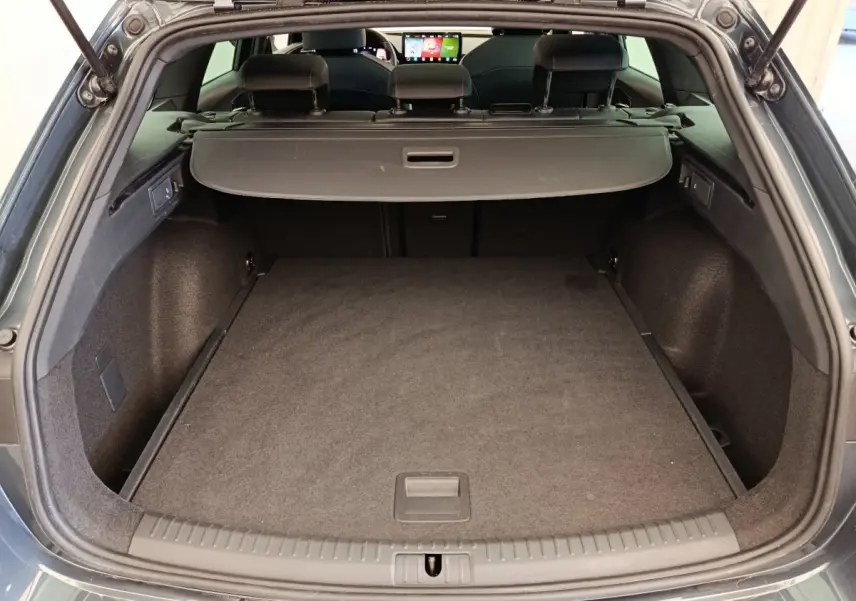 Coffre ouvert d'une CUPRA LEON ST gris foncé, vue arrière montrant l'espace de chargement et la tablette de séparation.