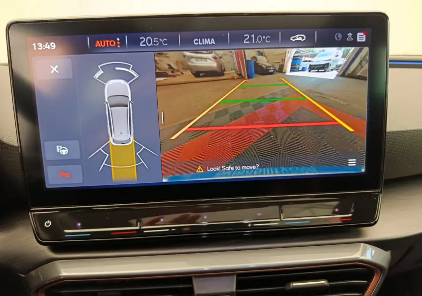 Écran tactile central montrant l'aide au stationnement arrière avec vue caméra sur tapis coloré, intérieur CUPRA Leon ST gris foncé 2024.