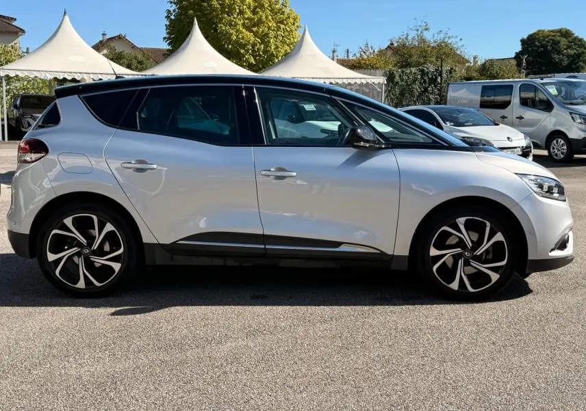 Profil côté gauche d'un Renault Scénic IV gris platine avec toit noir étoile, roues alliage au design moderne, en extérieur.