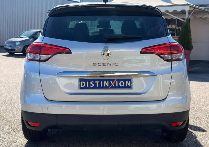 Vue arrière d'un Renault Scénic IV gris platine avec toit noir, mettant en valeur les feux arrière et le logo central.