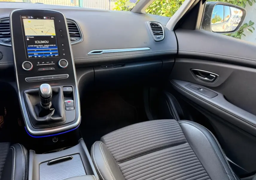 Intérieur avant droit du Renault Scenic IV gris platine, avec console centrale et levier de vitesse manuelle visible.