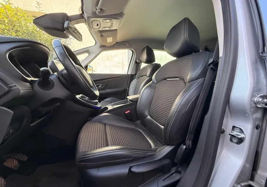 Vue intérieure côté conducteur du Renault Scenic IV 2020, sièges en cuir noir avec surpiqûres blanches et tableau de bord visible.