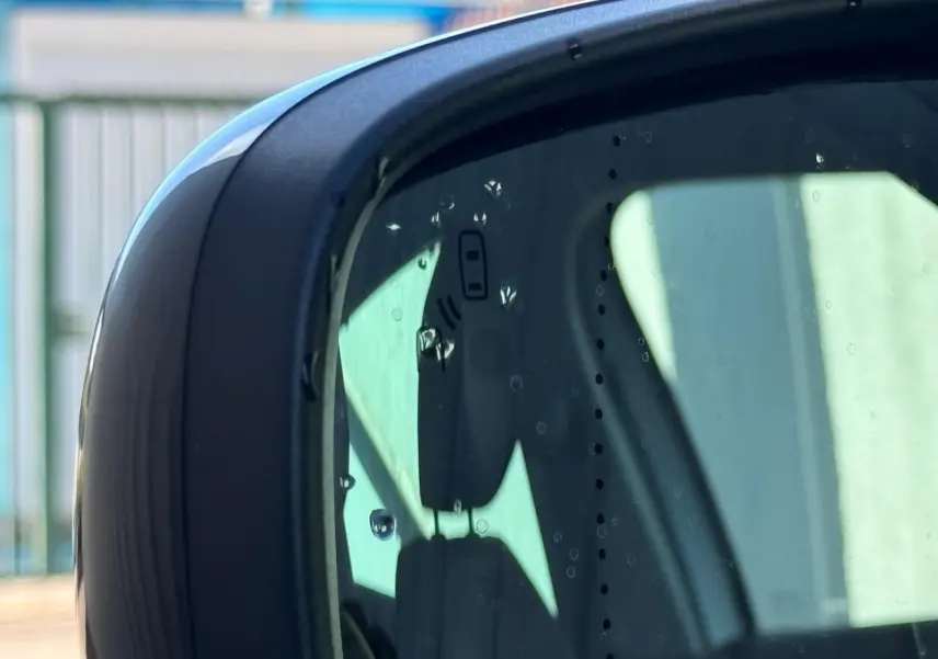 Rétroviseur extérieur droit du Renault Scénic IV gris platine avec toit noir, montrant un reflet partiel de l'habitacle.