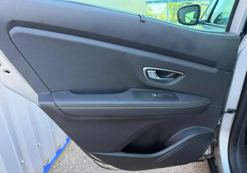 Porte intérieure côté gauche de Renault Scenic IV 2020 gris platine, avec poignée argentée et bouton de vitre électrique.