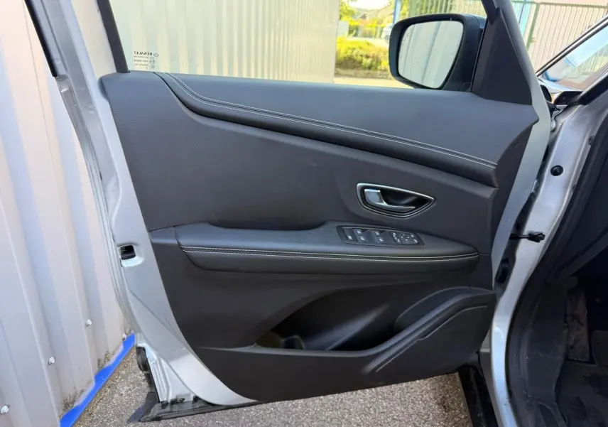 Porte avant gauche ouverte d'un Renault Scenic IV gris platine, avec garniture intérieure noire et commandes électriques.