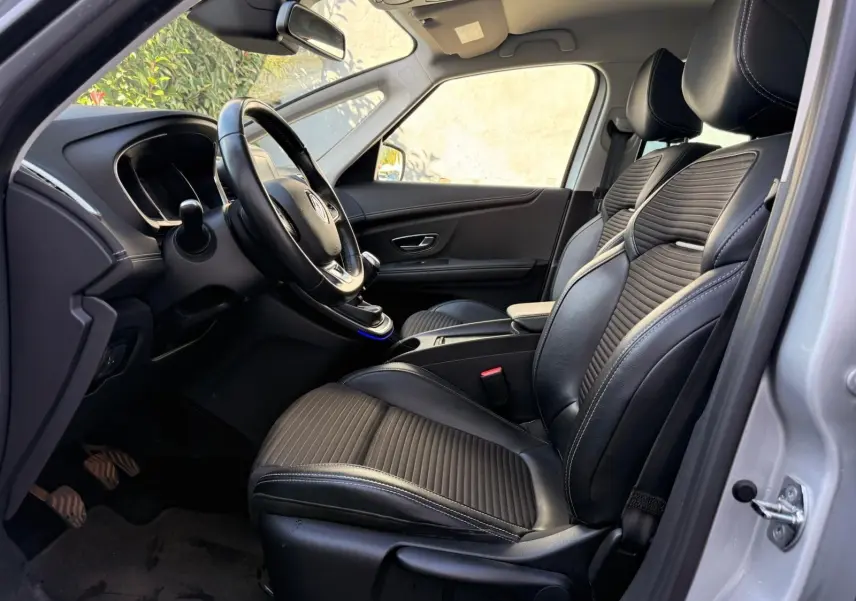 Vue intérieure côté conducteur du Renault Scénic IV 2020, sièges noirs en cuir avec surpiqûres et tableau de bord épuré.