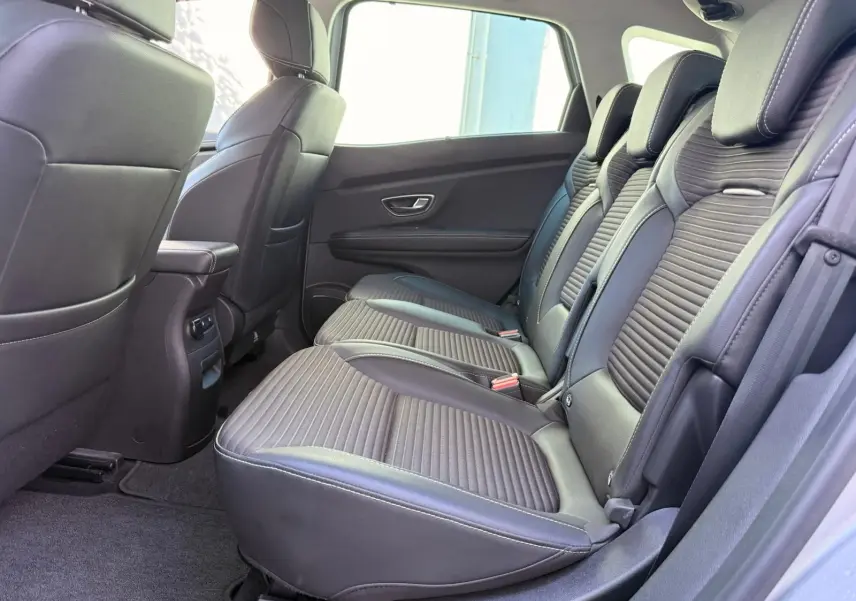 Vue latérale intérieure des sièges arrière en cuir noir du Renault Scenic IV gris platine, soulignant leur design moderne et confortable.
