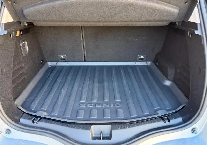 Coffre ouvert d'un Renault Scenic IV gris platine, vue arrière montrant le tapis de coffre marqué "SCENIC".