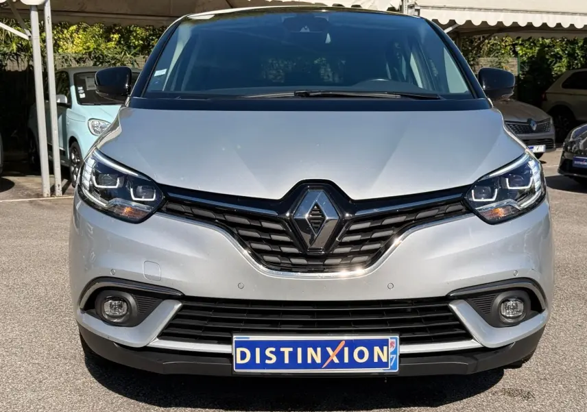 Vue frontale d'un Renault Scénic IV gris platine avec toit noir, mettant en valeur sa calandre et ses phares LED.