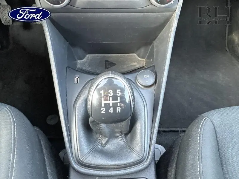 Gros plan sur le levier de vitesses manuel noir de la Ford Fiesta 2020, entouré des sièges en tissu gris foncé.