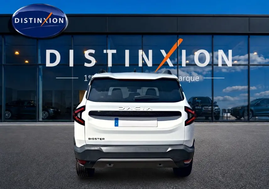 Vue arrière d'un Dacia Bigster blanc 2026 avec feux arrière en forme de C et logo Dacia visible sur fond de vitrine Distinxion.