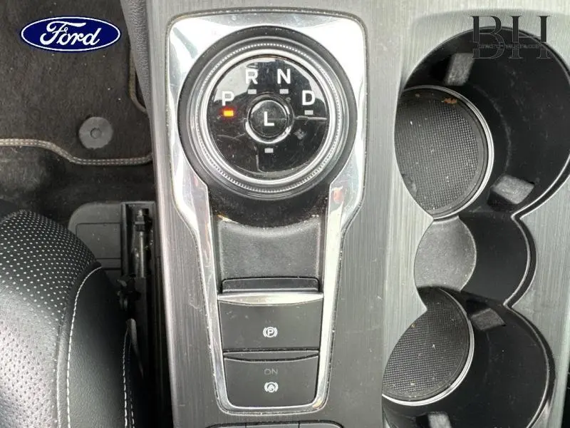 Vue plongeante sur la console centrale du Ford Kuga 2022, avec sélecteur rotatif de boîte auto et porte-gobelets noirs.