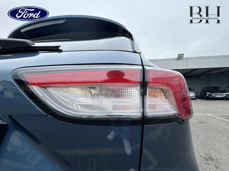 Gros plan sur le feu arrière droit bleu azur métallisé d'un Ford Kuga 2022 avec toit panoramique visible.