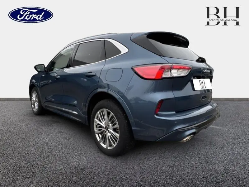 Vue 3/4 arrière droite d'un Ford Kuga bleu azur métallisé avec toit panoramique et jantes alu brillantes.