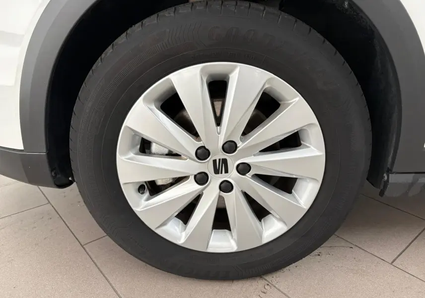 Gros plan sur la roue avant gauche du SEAT Arona blanc toit noir, avec jante en alliage argentée et logo central noir.