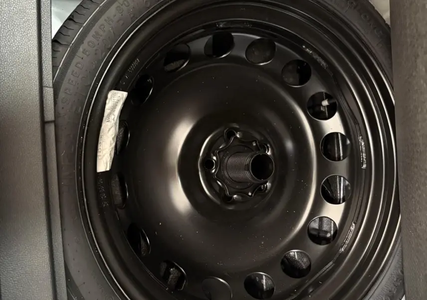 Gros plan sur la roue de secours noire dans le coffre d'un SEAT Arona blanc toit noir 2023.