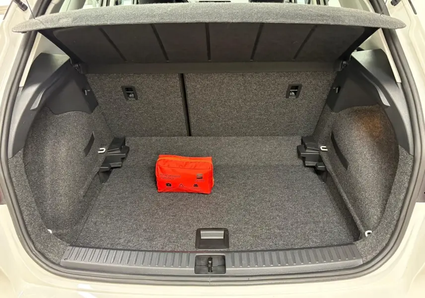 Coffre ouvert d'un SEAT Arona blanc toit noir, vue arrière, avec kit de sécurité rouge posé à l'intérieur.