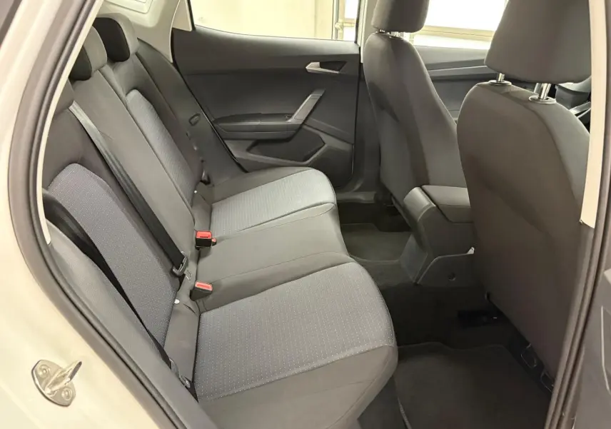 Vue intérieure côté gauche des sièges arrière gris foncé du SEAT Arona 2023 avec porte ouverte et accoudoir central avant visible.