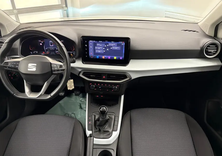 Intérieur avant du SEAT Arona 2023, tableau de bord moderne avec écran tactile et levier de vitesse manuel visible.