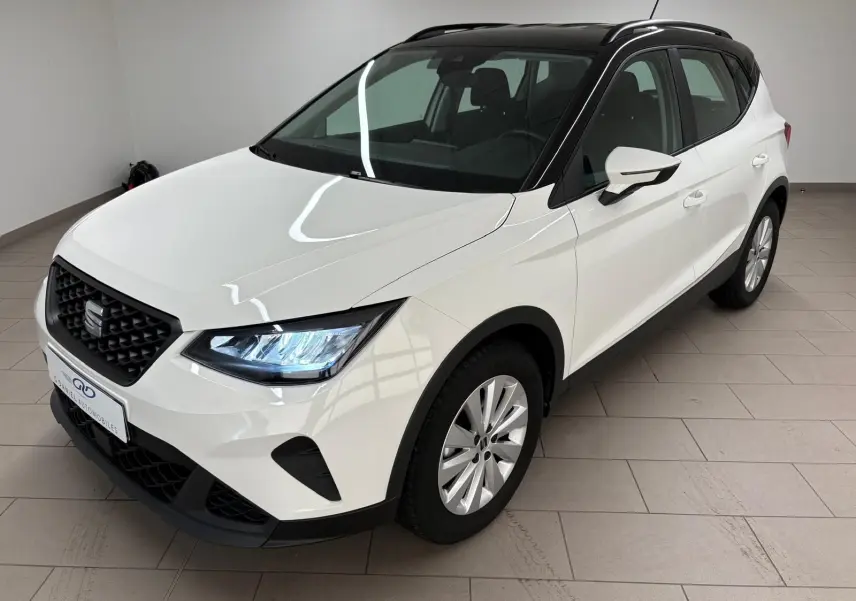 SEAT Arona blanc avec toit noir vu en 3/4 avant droit, mettant en valeur ses phares LED et sa calandre noire.