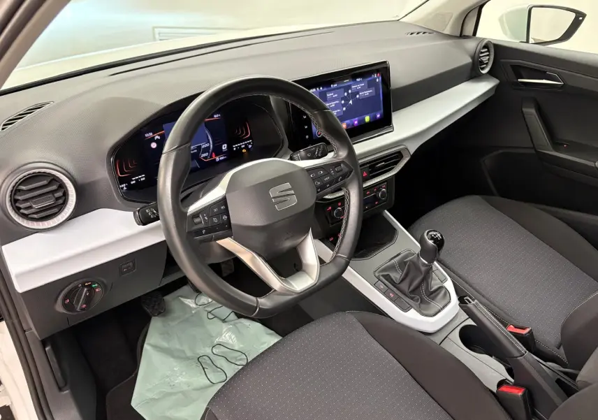 Intérieur du SEAT Arona 2023 vu côté conducteur, tableau de bord noir et gris avec volant multifonction et boîte manuelle.