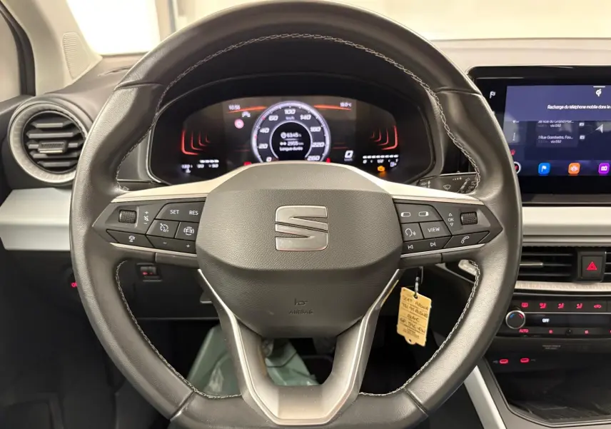 Vue rapprochée du volant en cuir noir du SEAT Arona 2023 avec tableau de bord numérique et écran tactile central.