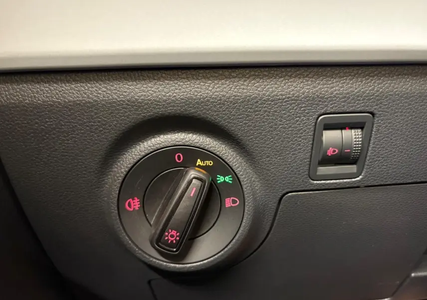 Gros plan sur la molette de réglage des phares du tableau de bord noir d'une SEAT ARONA 2023.